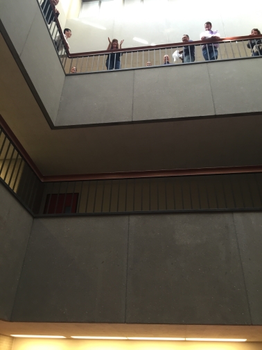 Photo taken of the third floor atrium from the bottom floor. People stand by the balcony watching the egg drops.